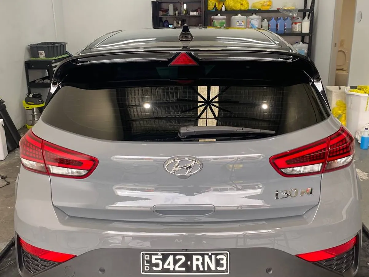 Shop lighting reflected in the ceramic coated rear of a Hyundai i30 N, Brisbane