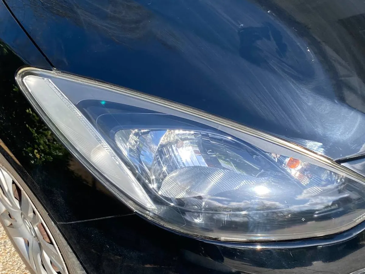 Hazy headlight on a black Mazda 2 before restoration
